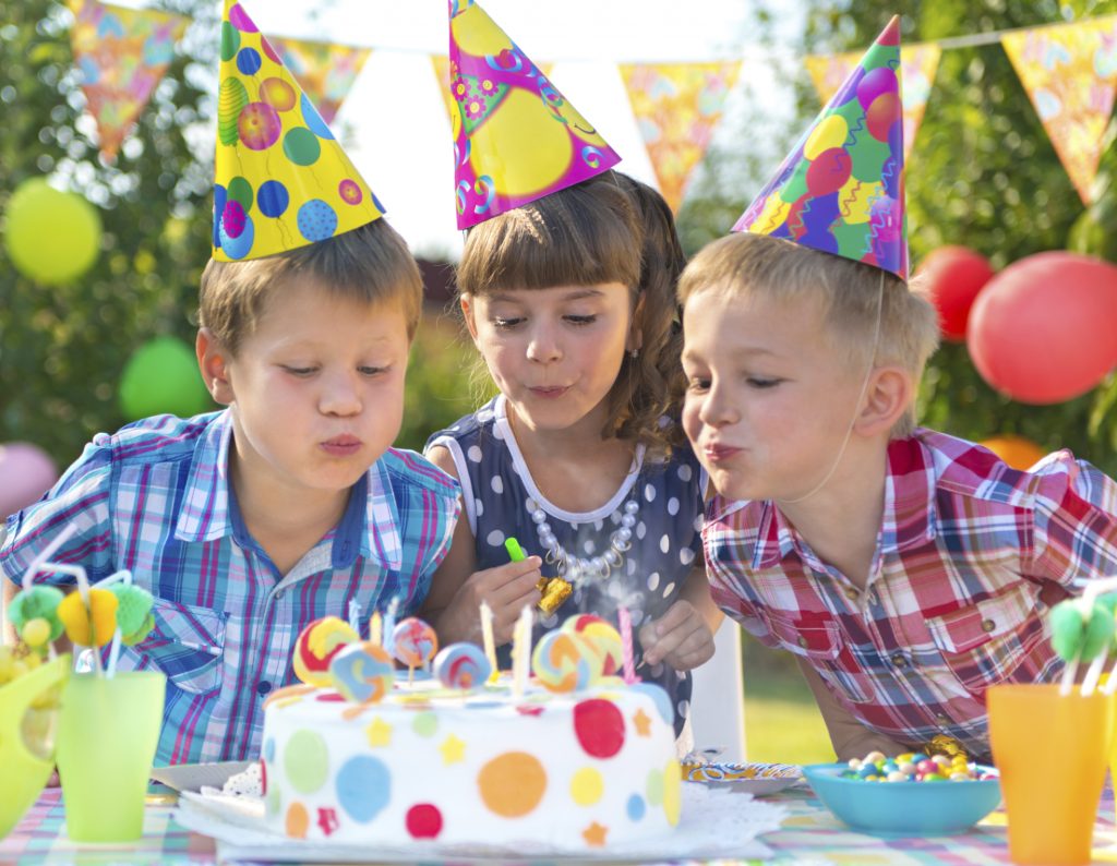 Kids at birthday party blowing candles on cake