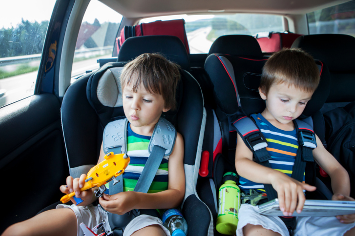 Two boy in car seats, traveling in car and playing