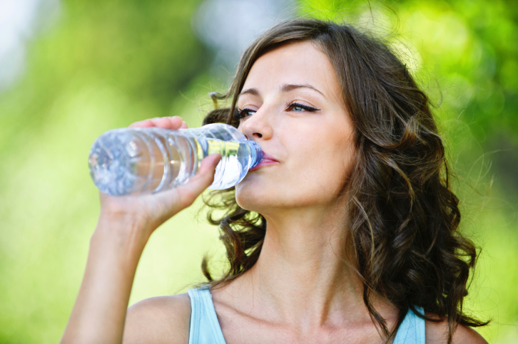 young dark-haired woman drinking water